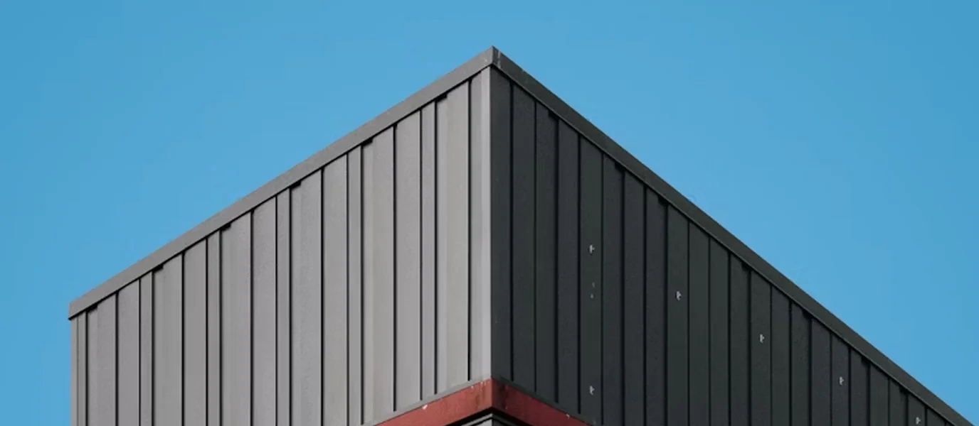 Dark metal cladding on the corner of a building under a blue sky