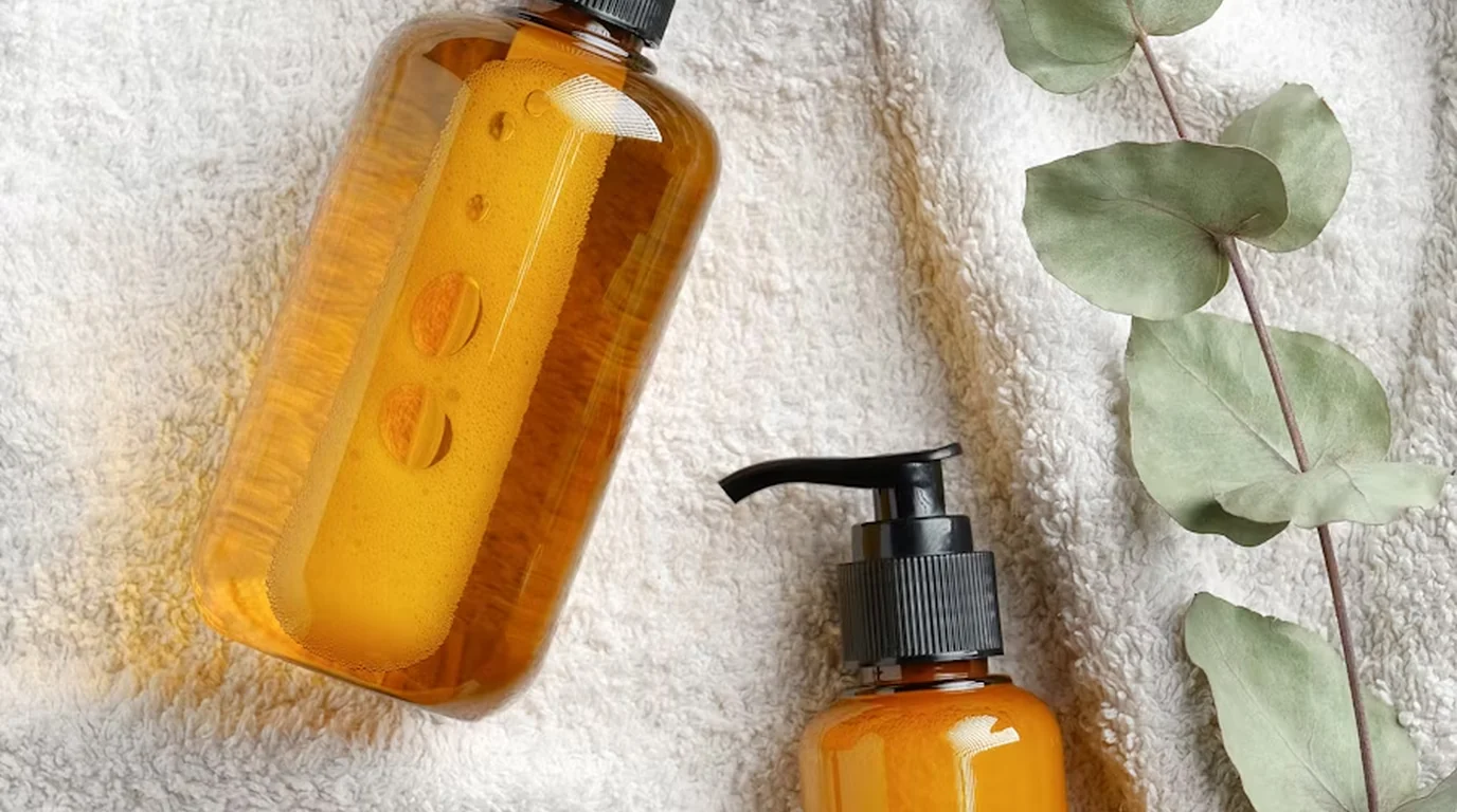 Skincare bottles on a towel with eucalyptus leaves